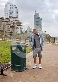 A man throws garbage in the trash can