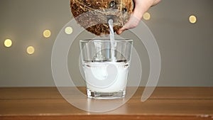 Man throws ice into a glass, then pours coconut water. Against the background of the lights