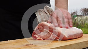 A man throws a piece of pork on a chopping Board. cutting meat into pieces