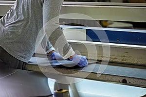 Man is thrusting a metal sheet in a slit.