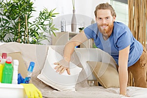 man tidying up sofa