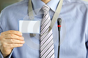 Man in tie shows blank badge attending seminar