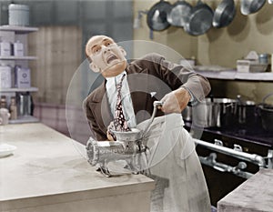 Man with tie stuck in meat grinder photo