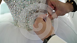 Man tieing lace on wedding dress
