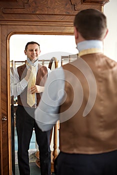 Man tieing tie in front of mirror