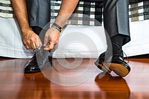 Man ties his shiney new black leather business shoes.