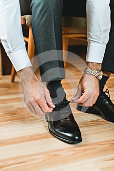 Man ties his shiney new black leather shoes