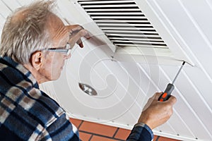 Man tightening the bolts on ventilation grille