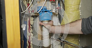 Man tightly twists a flask with a filter for water purification with a special key.