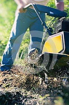 The man tills the soil with the motor cultivator