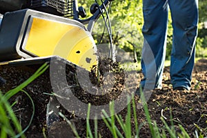 The man tills the soil with the motor cultivator