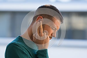 Man with tinnitus. Man touching his ear because of strong earache or ear pain. Otitis