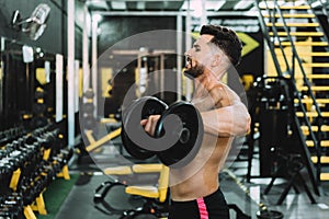 Man with tired expression doing exercises with weight in a gym