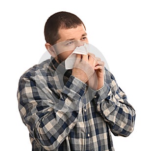 Man with tissue suffering from runny nose on white background