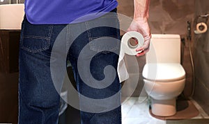 Man in a toilet holding tissue paper roll