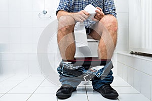 Man in toilet holding tissue paper roll