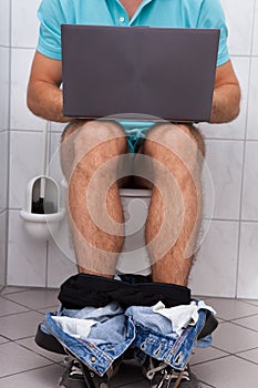 Man in toilet using laptop