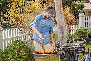 Man with tongs cooking on a back yard barbecue