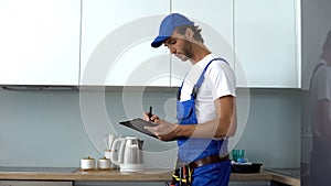 Man with tools writing report inspecting kitchen on electrical safety, service