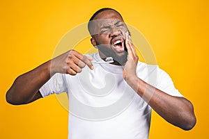 Man with tooth brush and toothache. Image of young shirtless African man holding a toothbrush with toothpaste and apple, while