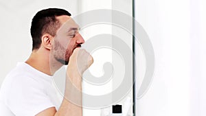 Man with toothbrush cleaning teeth at bathroom