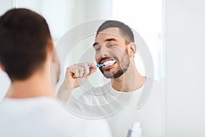 Man with toothbrush cleaning teeth at bathroom