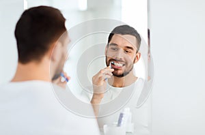 Man with toothbrush cleaning teeth at bathroom