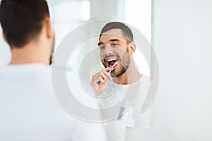 Man with toothbrush cleaning teeth at bathroom