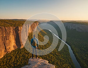 A man on top against the backdrop of a mountain valley at sunset