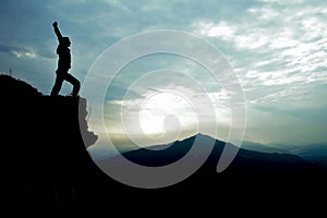 Man on top of cliff with arms raised