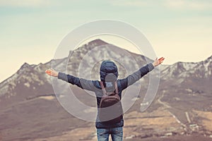 Man on top mountains on background mountains with arms raised in air. view from back