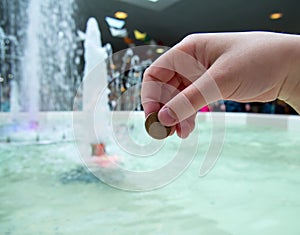 A man tosses a coin into a fountain