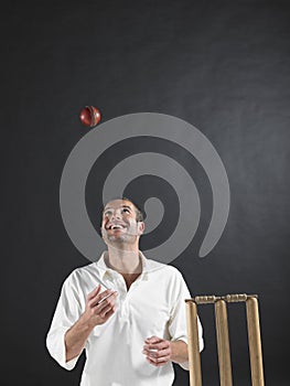 Man Tossing Cricket Ball By Stumps In Air