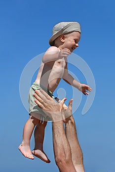 Man tossing little boy, blue sky in the background