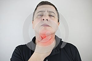 Man touches a sore throat and neck, twists from irritation and inflammation. Sore throat when swallowing, suspected pharyngitis