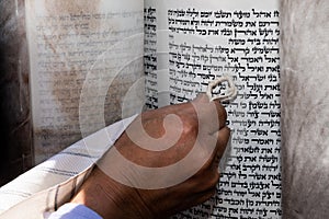 Man touches the text of a Torah scroll with his tzitzit