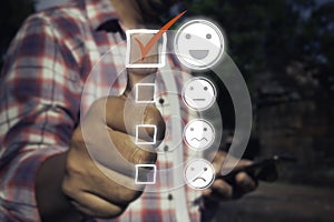 A man touching check mark icon and face emoticon smile on dark background.Customer service, service mind,service rating