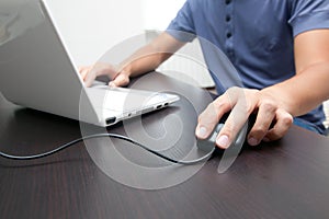 Man touching computer mouse and typing on a pc