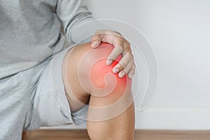 A man touching knee with red highlights concept of knee and joint pain photo