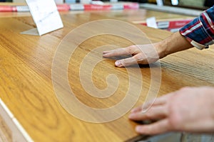 Man touching wood texture of laminate floor sample in flooring shop