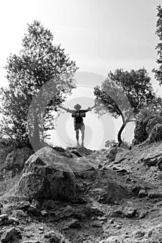 Man Tourism traveler hiker with a backpack standing on the rock hands up enjoi nature with olive trees, travel Hiking adventure