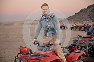 Man tourist with arafatka on quad bike ATV safari in desert Arab Emirates, Egypt