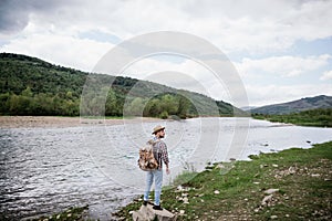 Man tourist with a backpack travels along the mountain river. Copy spase