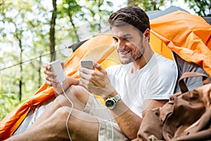 Man tourist charging battery of mobile phone in touristic tent