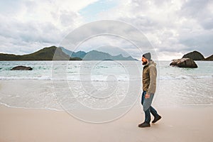 Man tourist enjoying ocean view walking on sandy Haukland beach traveling in Norway