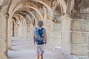 Man tourist explores Aspendos Ancient City. Aspendos acropolis city ruins, cisterns, aqueducts and old temple. Aspendos