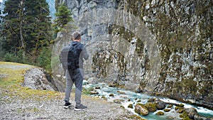 Man tourist hiker with backpack enjoying scenic view mountain river landscape. Travel hiker looking away. Travel, people