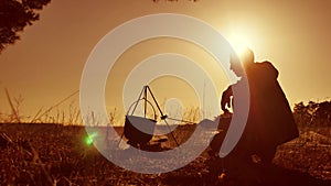 Man tourist hiker lifestyle are beer sitting by bonfire halt party in nature camping silhouette sunlight sunset. man