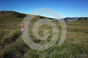 Man tourist hiking on grassy terrain beautiful hilly landscape in Puyehue National Park, Los Lagos Region