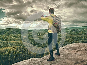 Man tourist hiking mountain trail, takes picture by phone